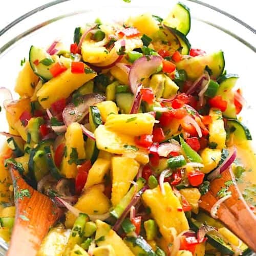 Dressing a salad with refreshing pineapple and cucumbers along with other veggies.
