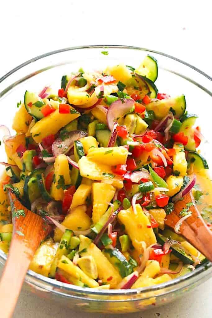 Dressing a salad with refreshing pineapple and cucumbers along with other veggies.