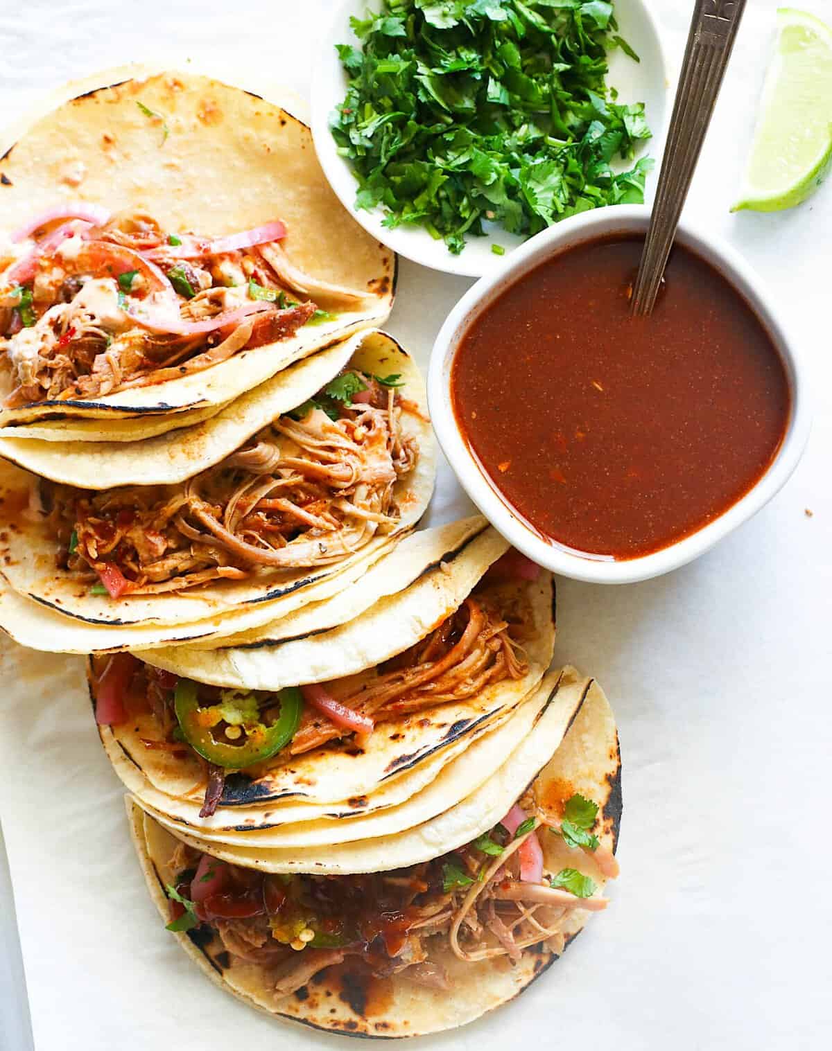 Hot sauce and cilantro with corn tortillas filled with smoked pulled pork.