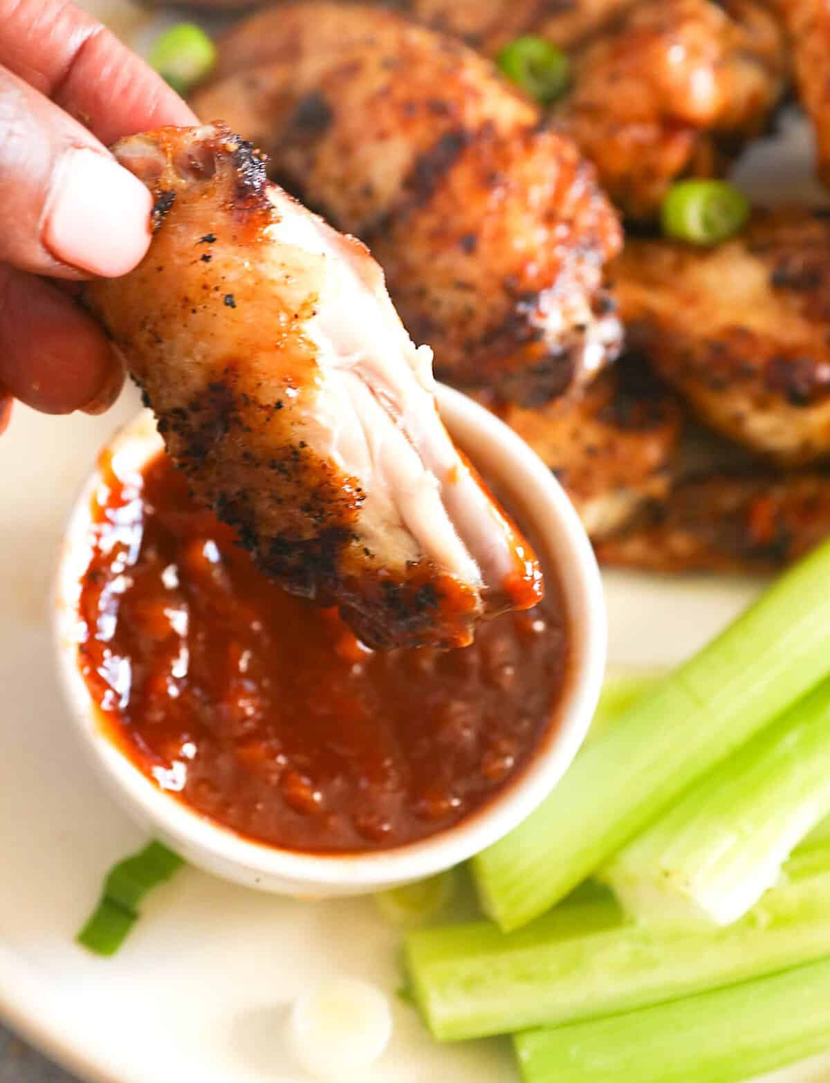Dipping flavorful and fall-off-the-bone tender chicken wings into homemade BBQ sauce.