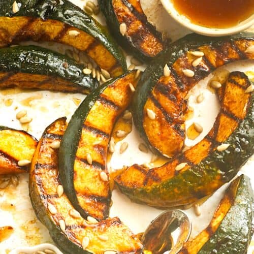 Grilled acorn squash sweetened with maple syrup, holiday spices, and toasted nuts.