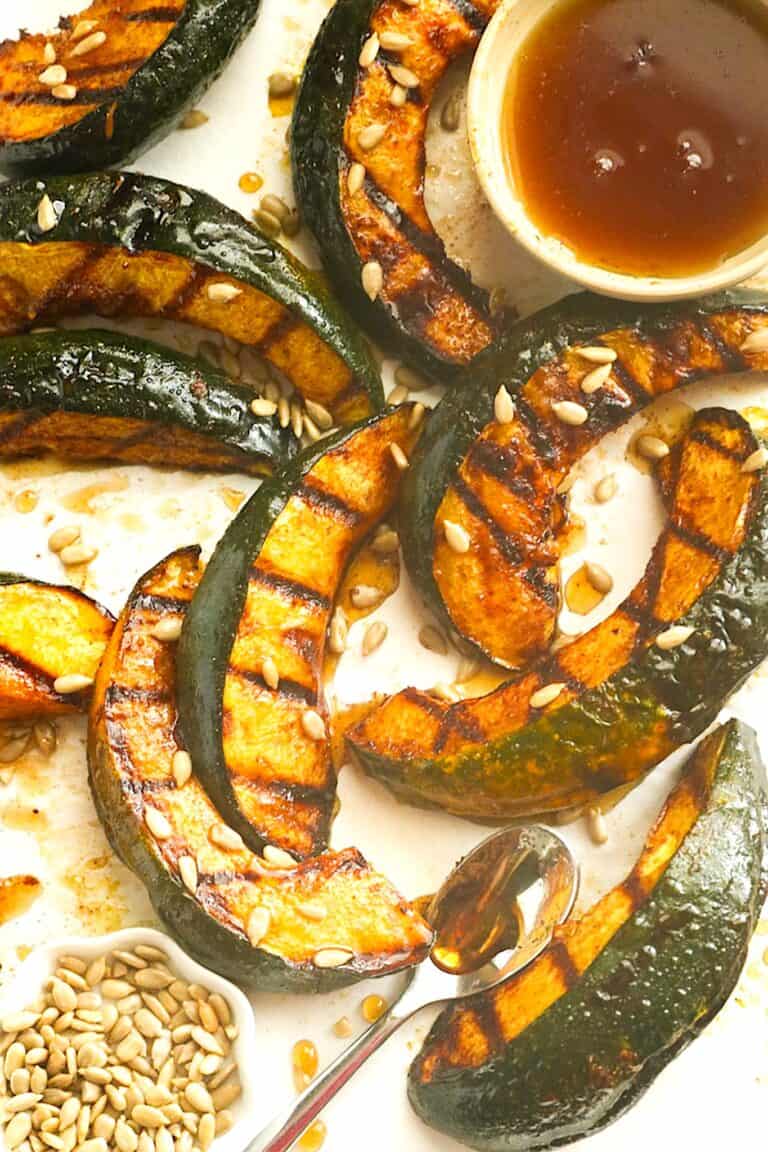 Grilled acorn squash sweetened with maple syrup, holiday spices, and toasted nuts.