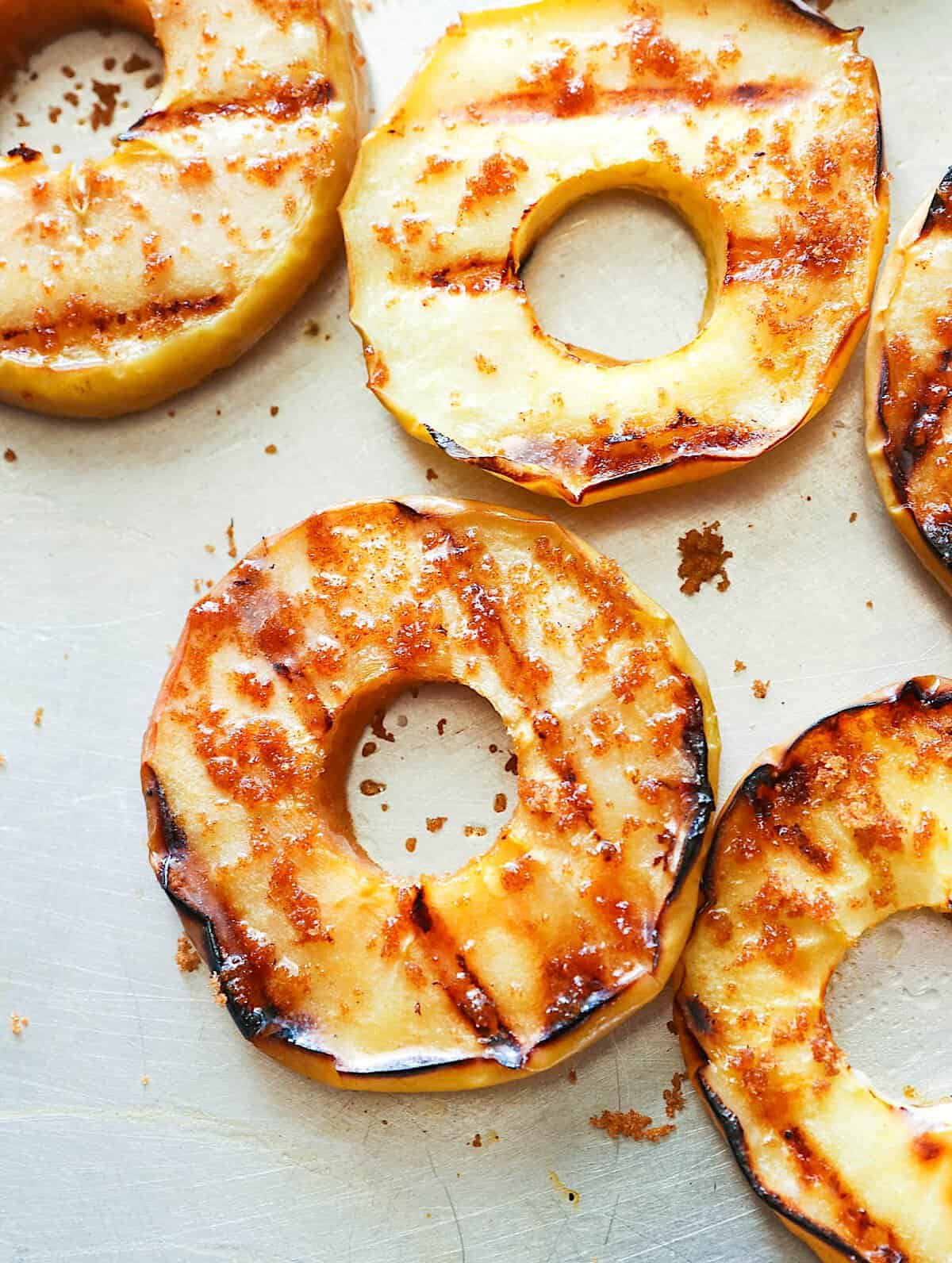 Sprinkling grilled apples with cinnamon sugar for a versatile dessert or snack.