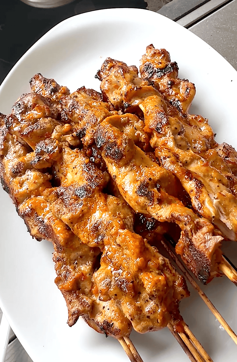 A white platter loaded spicy, mouthwatering peri peri marinated chicken skewers.