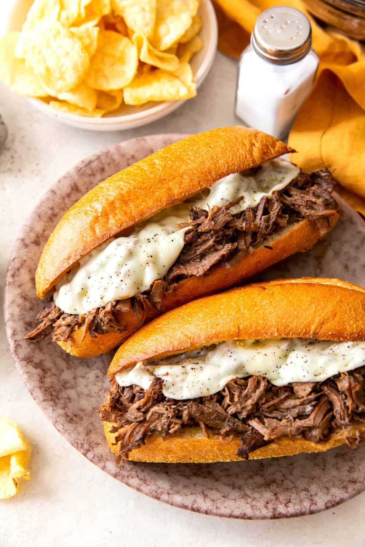 A mouthwatering slow cooker French dip sandwich ready to enjoy with potato chips.