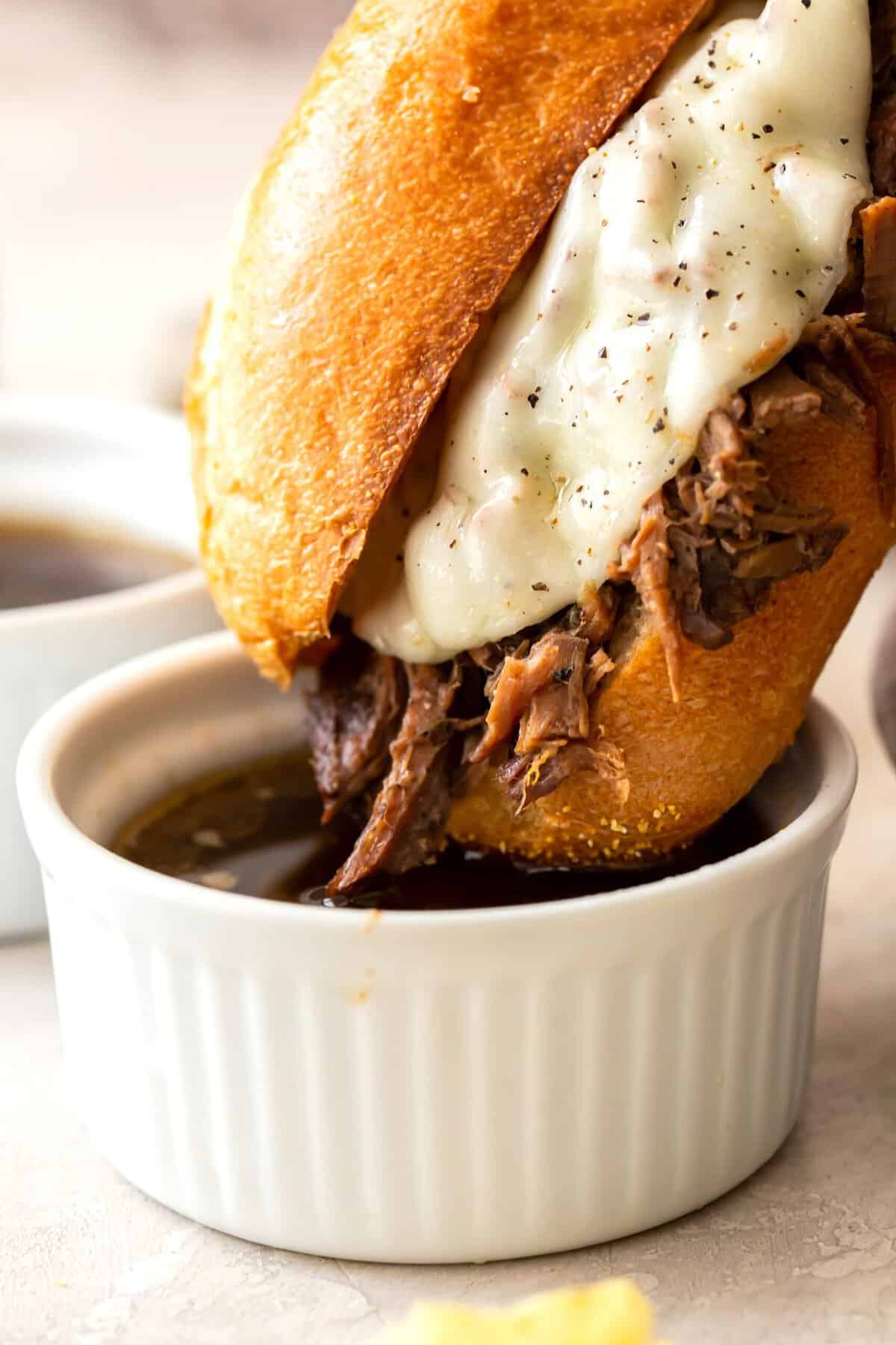 Dipping a roast beef sandwich on a French roll into au jus for a deliciously messy experience.