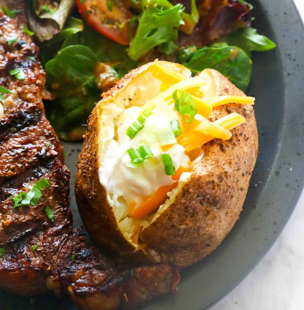 Serving up smoked baked potatoes with steak and a salad for a healthy dinner.
