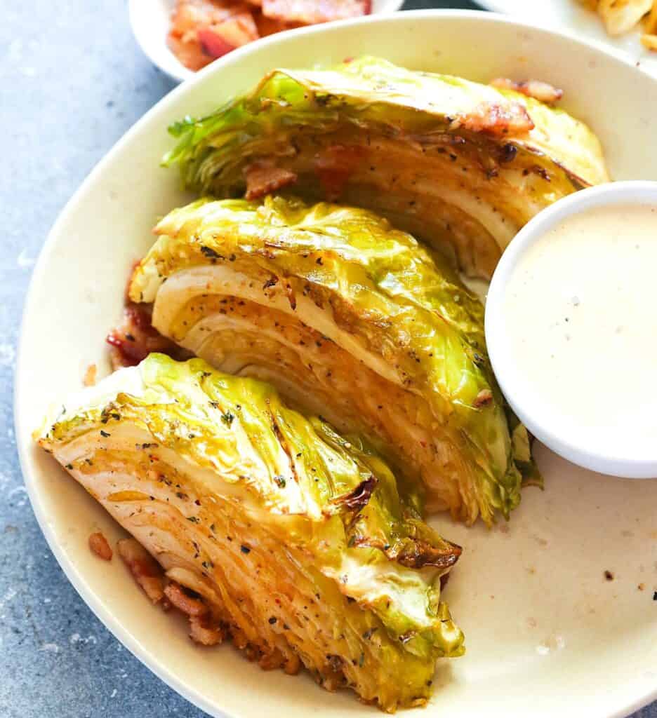 Smoked cabbage wedges garnished with bacon bits and served with remoulade sauce.
