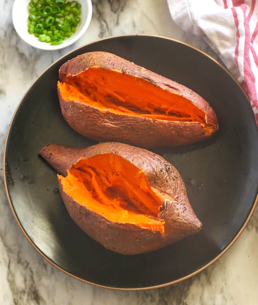 Two smoked sweet potatoes ready to enjoy with butter and green onions.