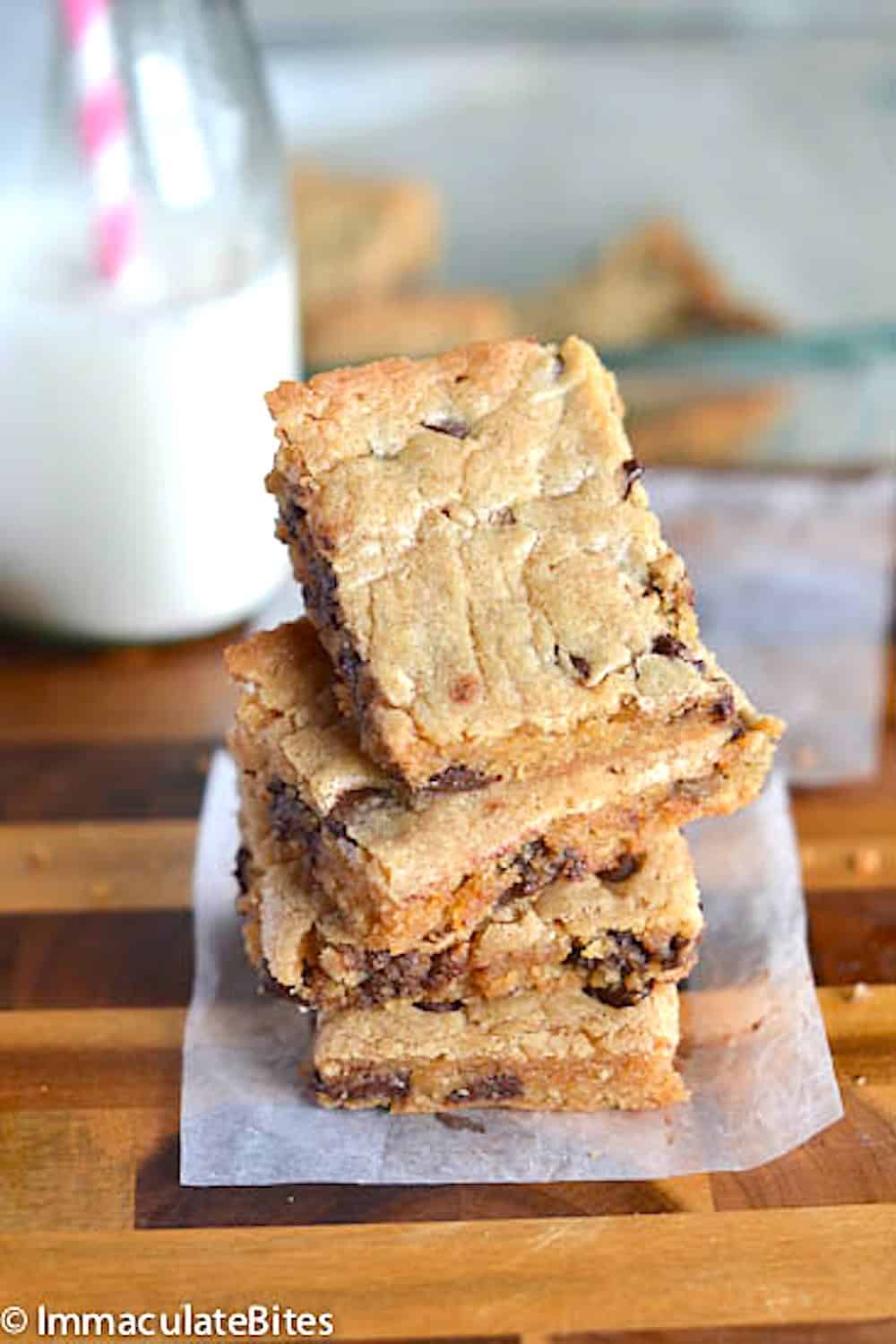 A stack of chocolate chip blondies ready to enjoy with a glass of homemade coconut milk.