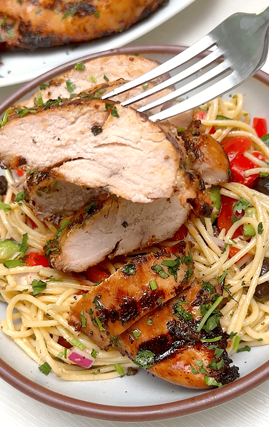 Slicing into a freshly grilled chicken breast that was marinated for extra juiciness.