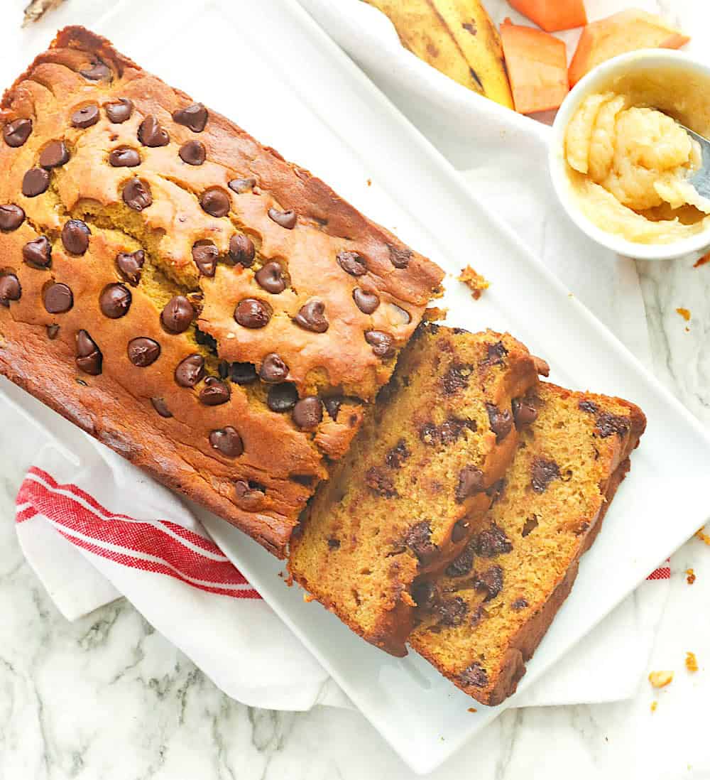 Slicing into freshly baked pumpkin banana bread loaded with chocolate chips.