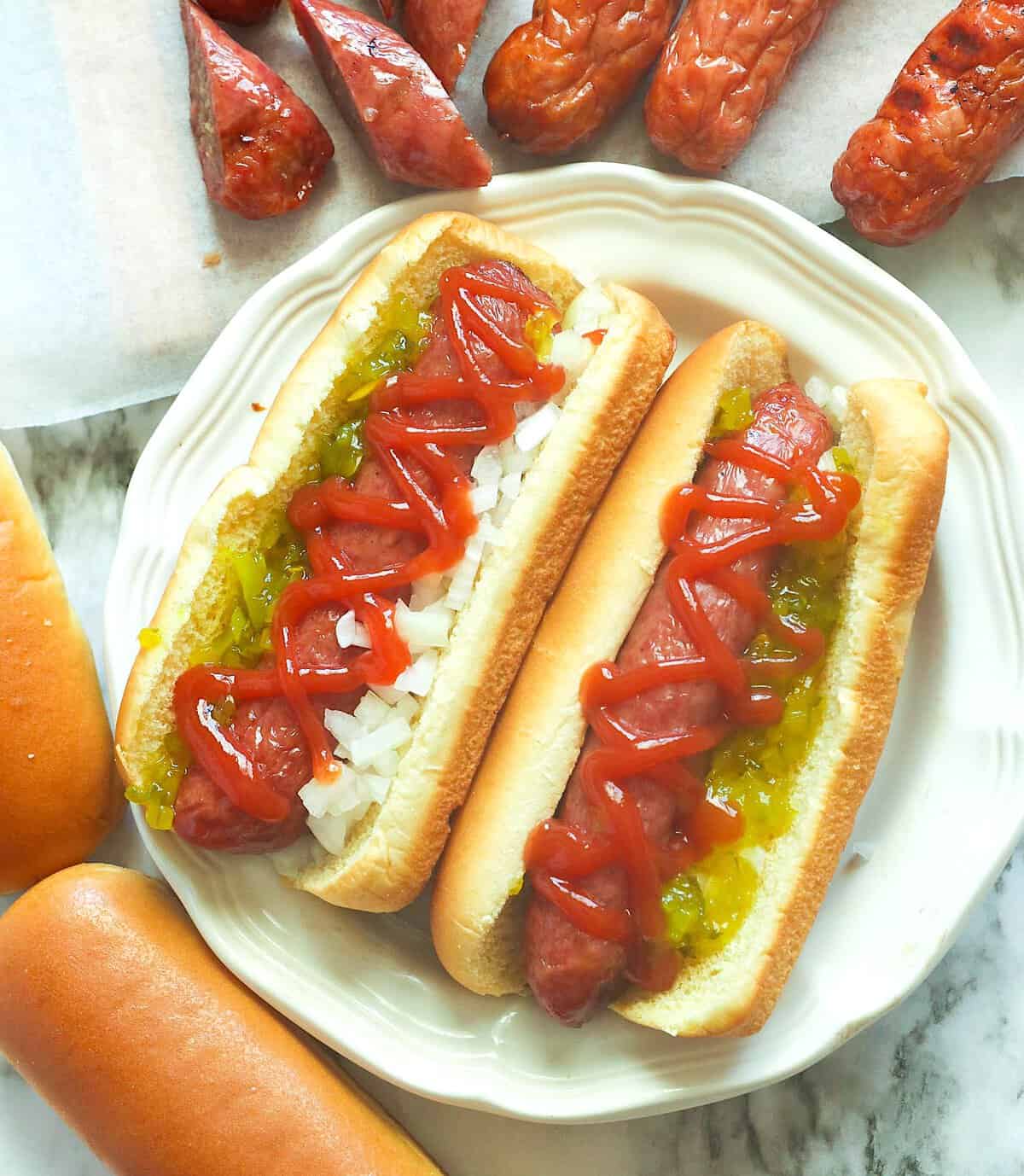 Enjoying freshly pellet grilled links in a hot dog bun with onions, relish, and ketchup for an easy cookout.