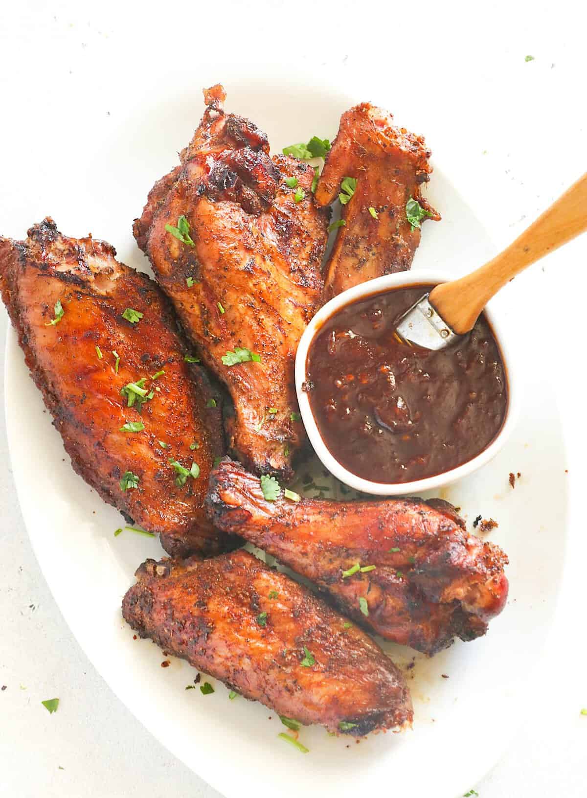 Enjoying smoked turkey wings with homemade BBQ sauce for a delicious twist on a holiday dinner.