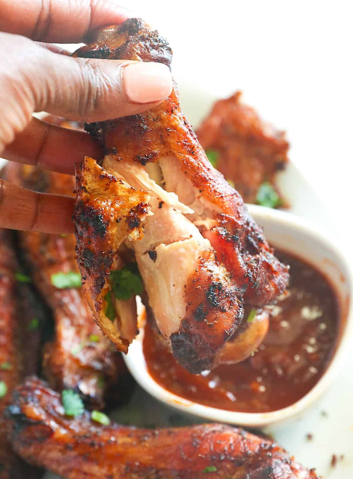 Dipping a tender, juicy turkey wing in BBQ sauce for a tasty cookout.