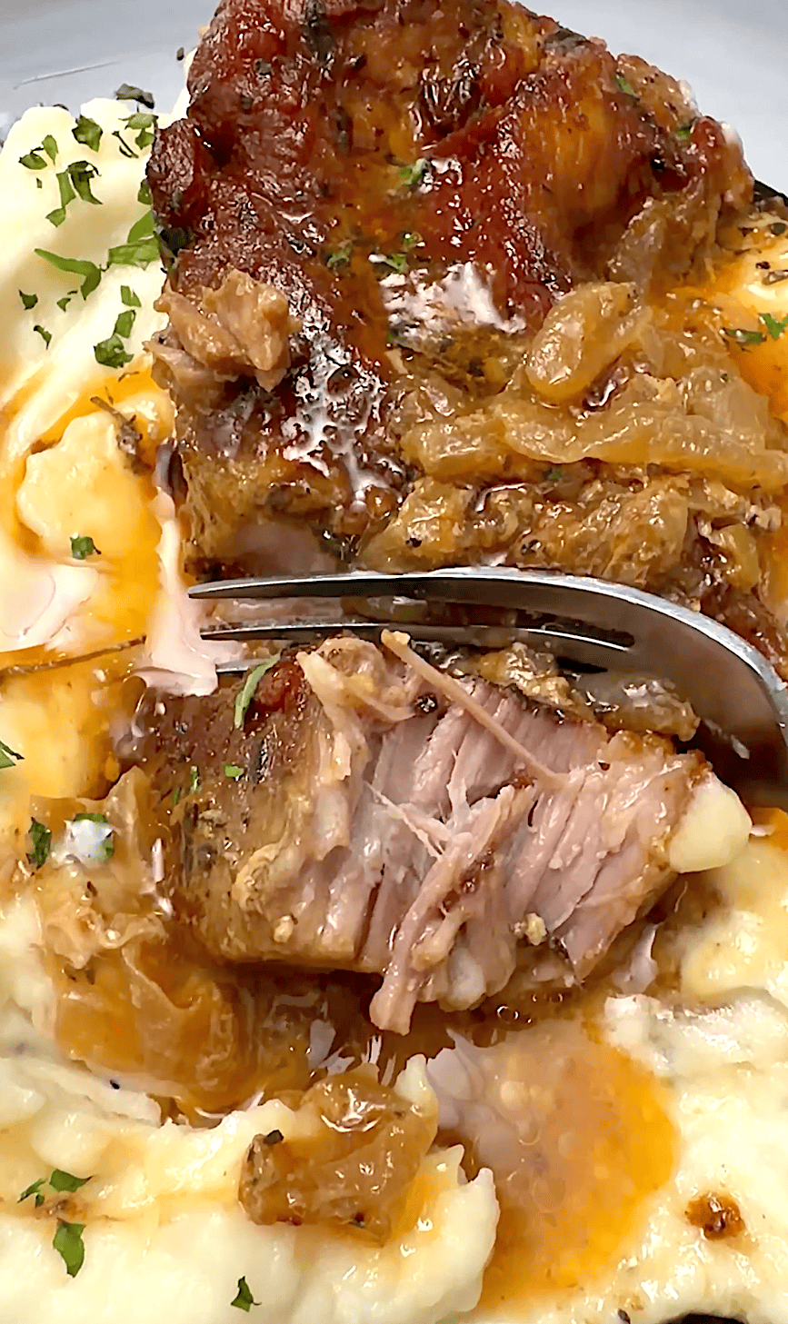 Forking into a tender, juicy pork chop smothered with pan drippings over mashed potatoes.