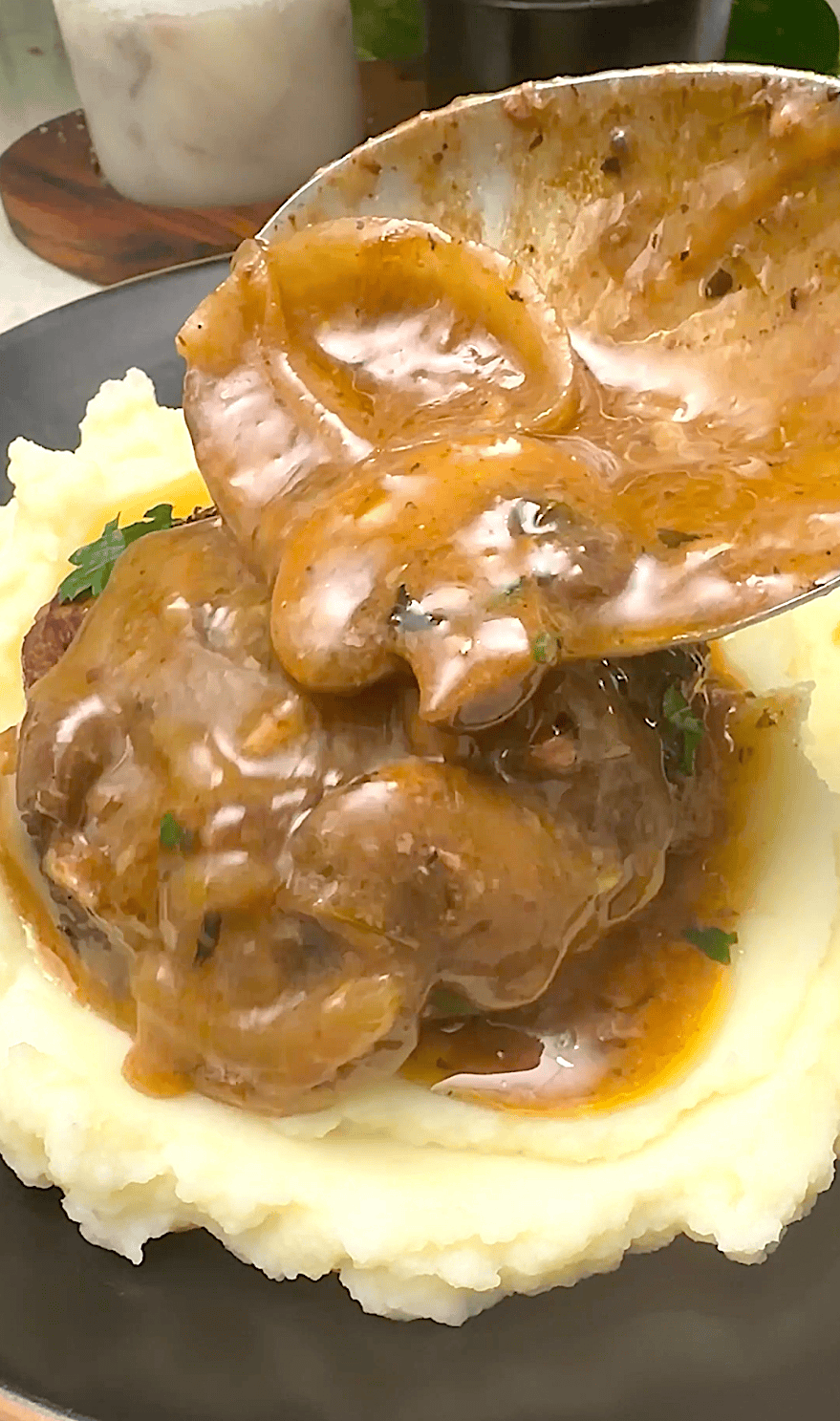 Drizzling the mushroom gravy over hamburger steaks and gravy with mashed potatoes.
