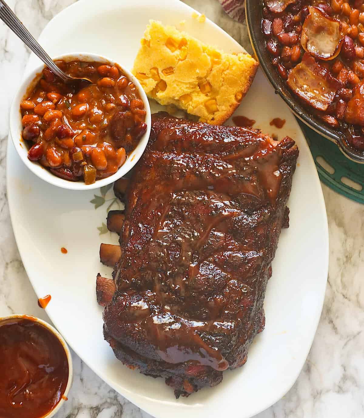 Serving smoked ribs with baked beans and cornbread.