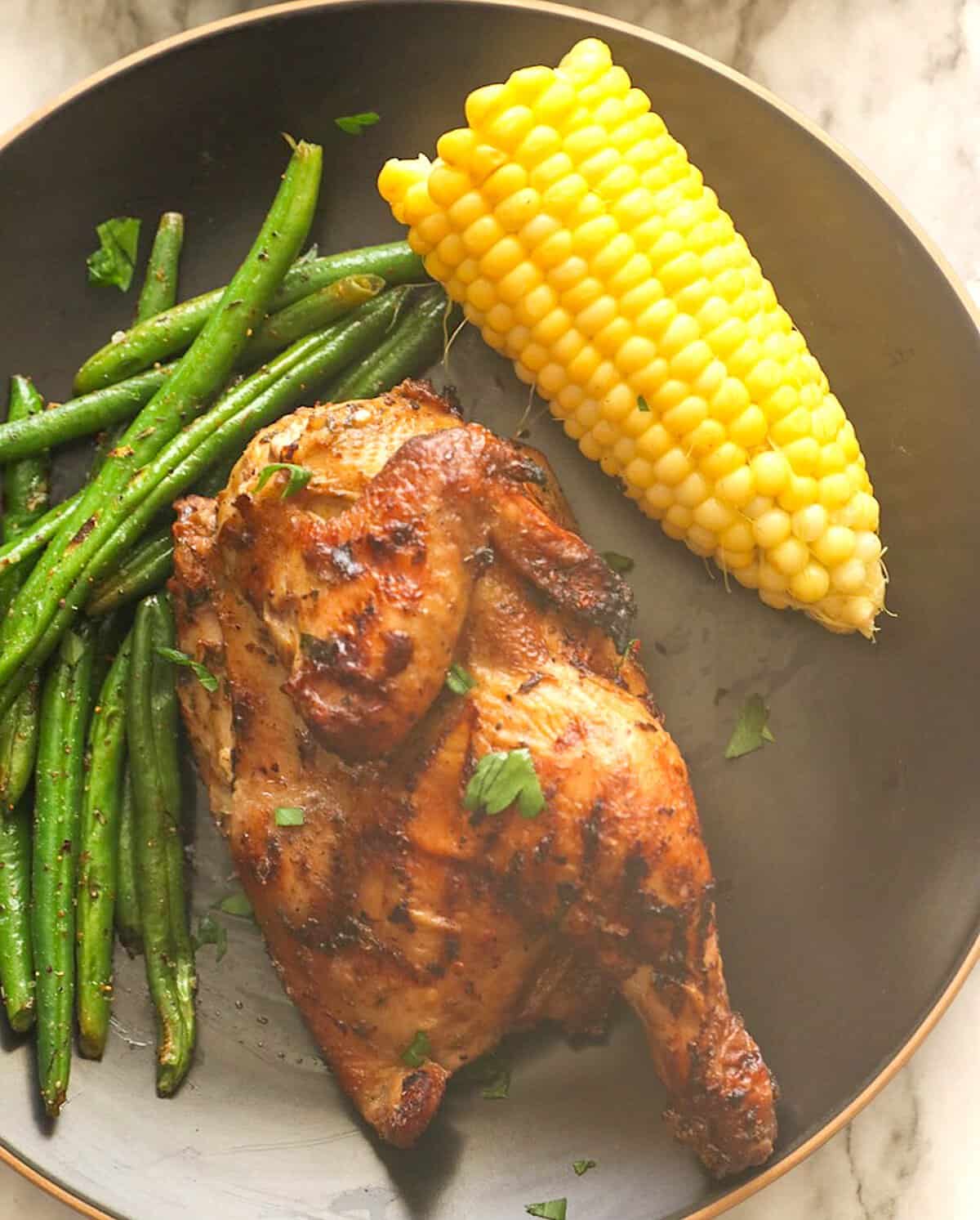 Freshly grilled Cornish hens with corn on the cob and green beans for a healthy dinner for celebrations.