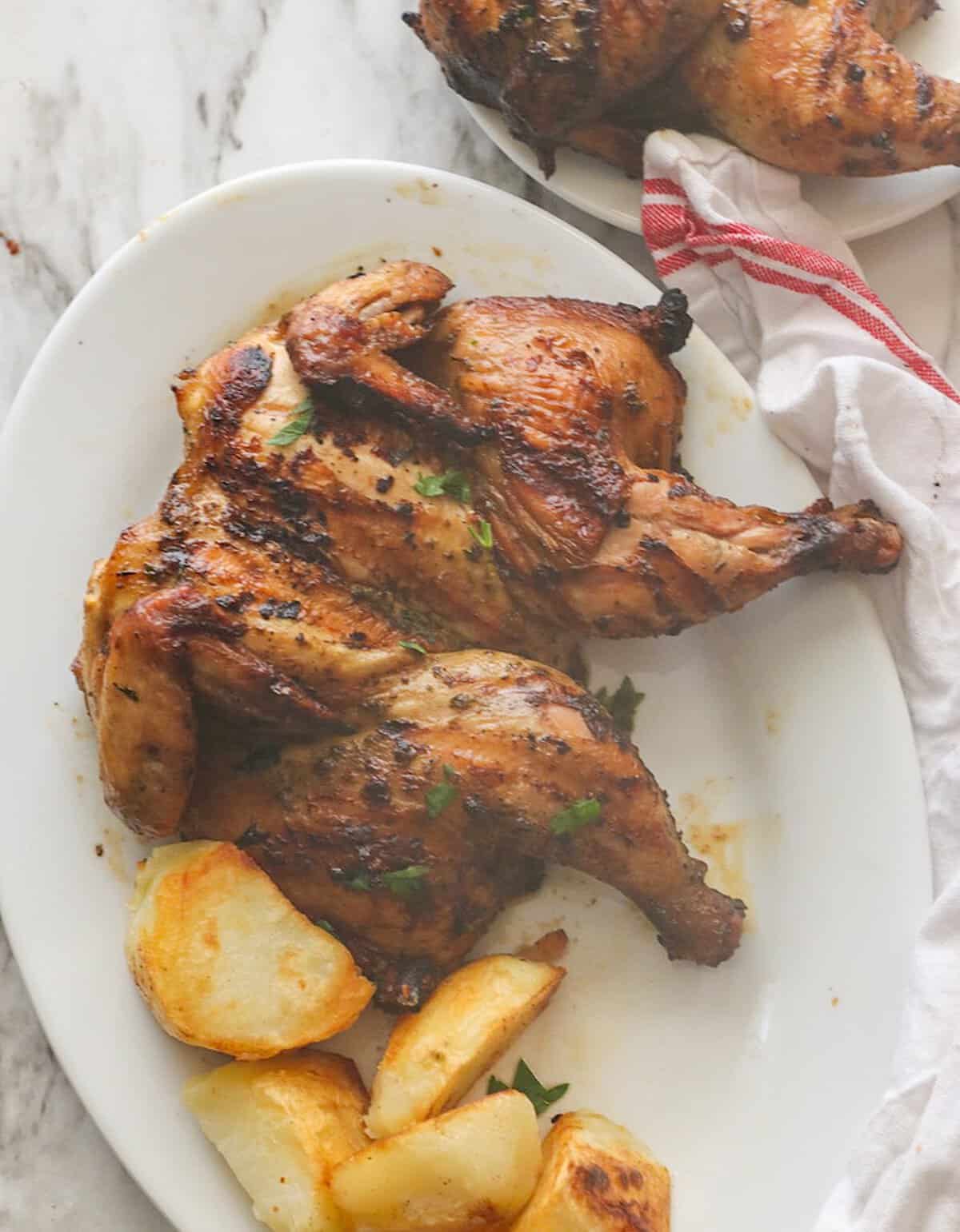A Cornish hen fresh from the grill with roasted potatoes for a lovely Christmas dinner.