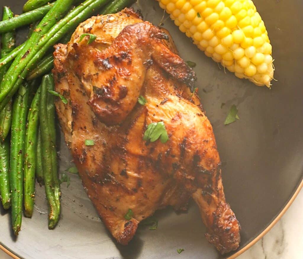 Serving up grilled Cornish hen with corn on the cob and green beans for an elegant dinner.