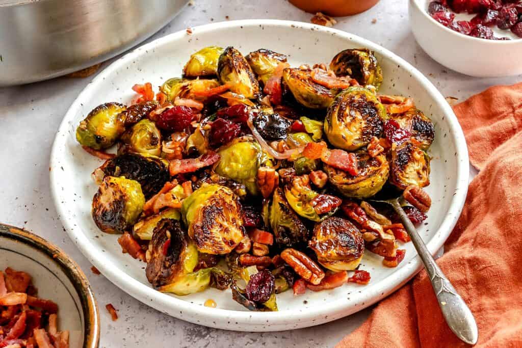 Loaded holiday Brussels sprouts perfectly glazed with a maple balsamic reduction, and made even better with bacon, pecans, and cranberries.