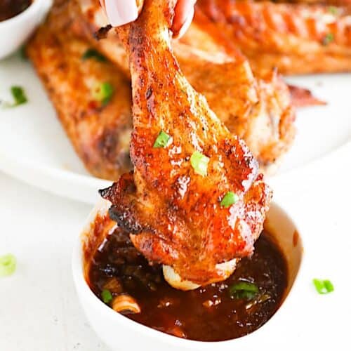 Dipping easy baked turkey wings into a mouthwateringly spicy sticky sauce.