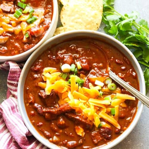 Enjoying a comforting, hot bowl of smoked brisket chili topped with grated cheese and sliced green onions.