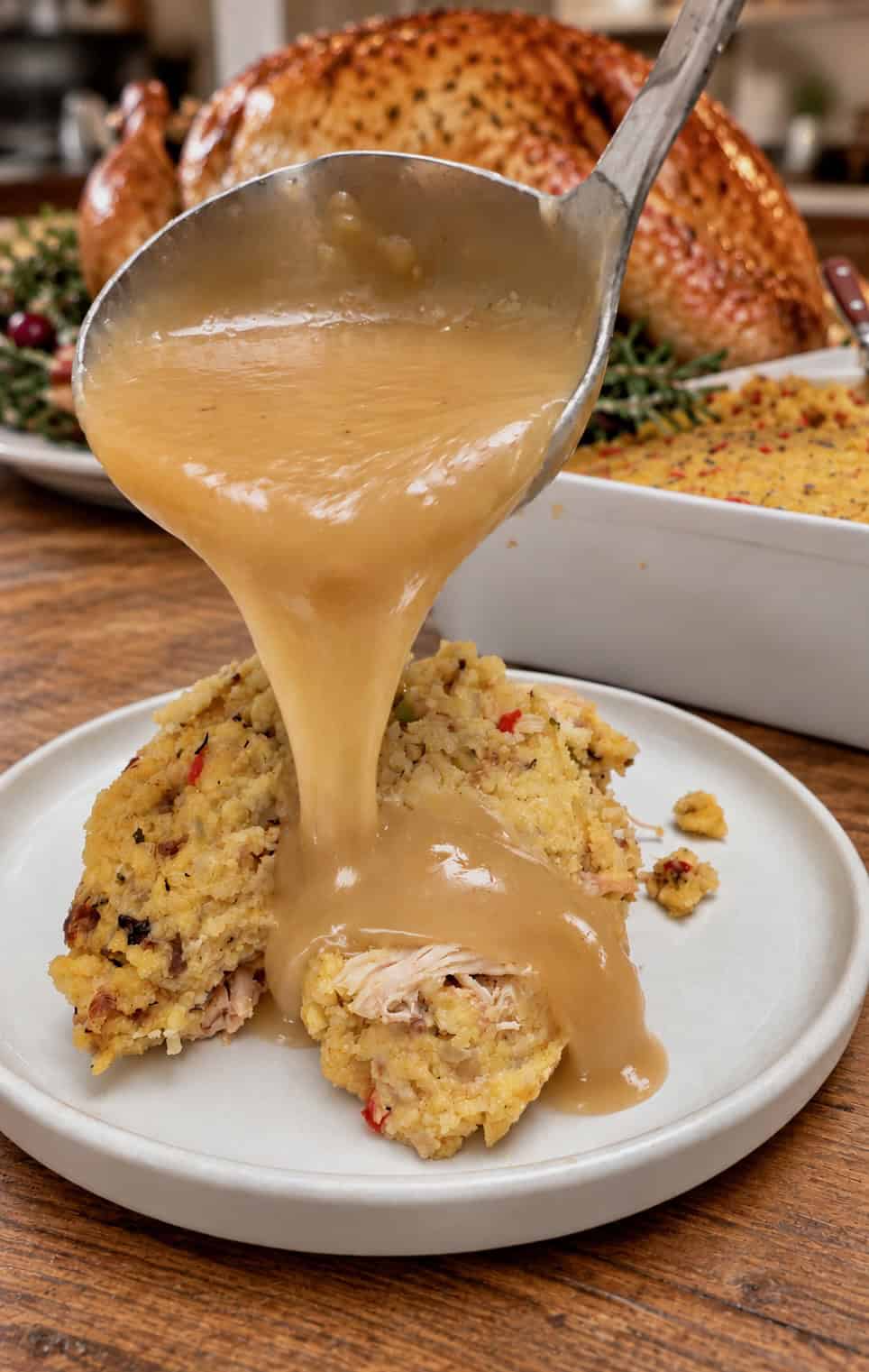 Drizzling homemade gravy over Southern cornbread dressing for a decadent side dish on Thanksgiving.